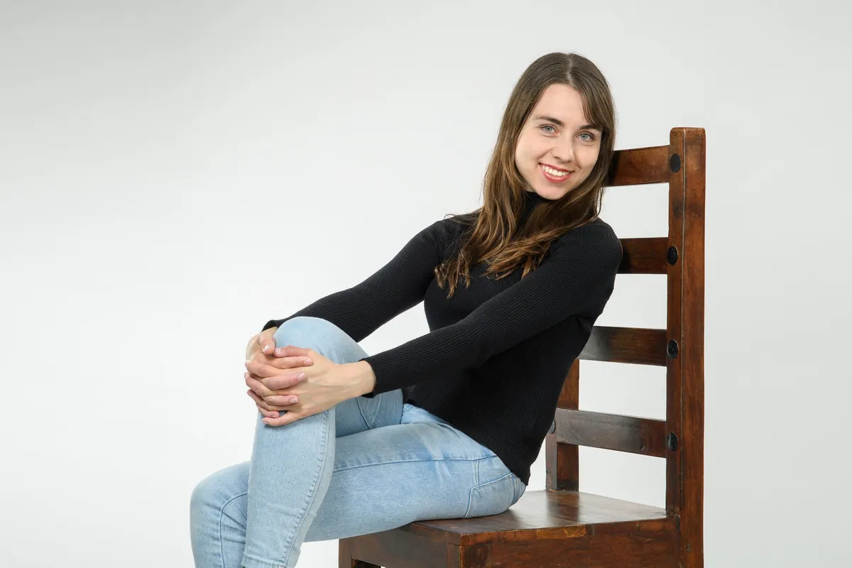 Porträt von Vicky im schwarzen Pullover auf einem Holzstuhl