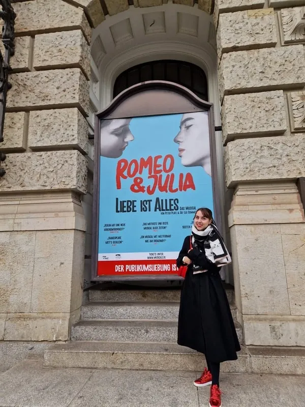 Vicky vor dem Plakat von „Romeo & Julia – Liebe ist alles“ an einer Theaterfassade
